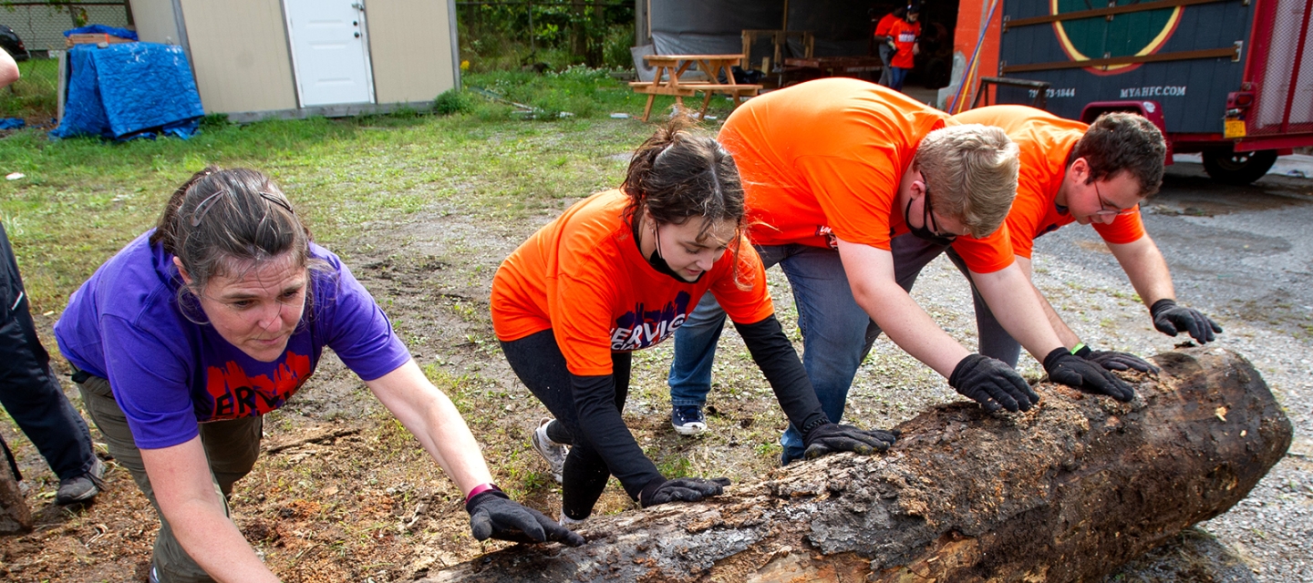 Volunteers pushing a log